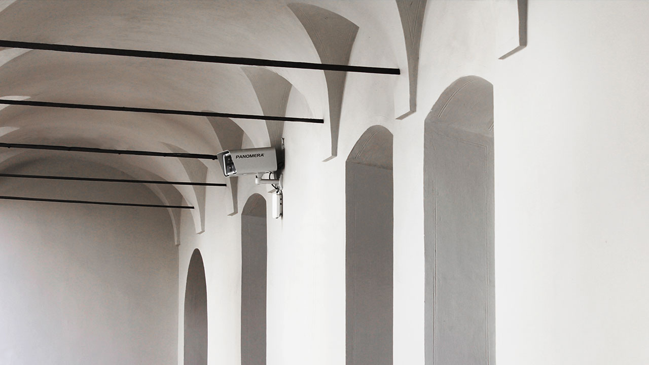 A white Panomera® multifocal camera blending in a white hallway.