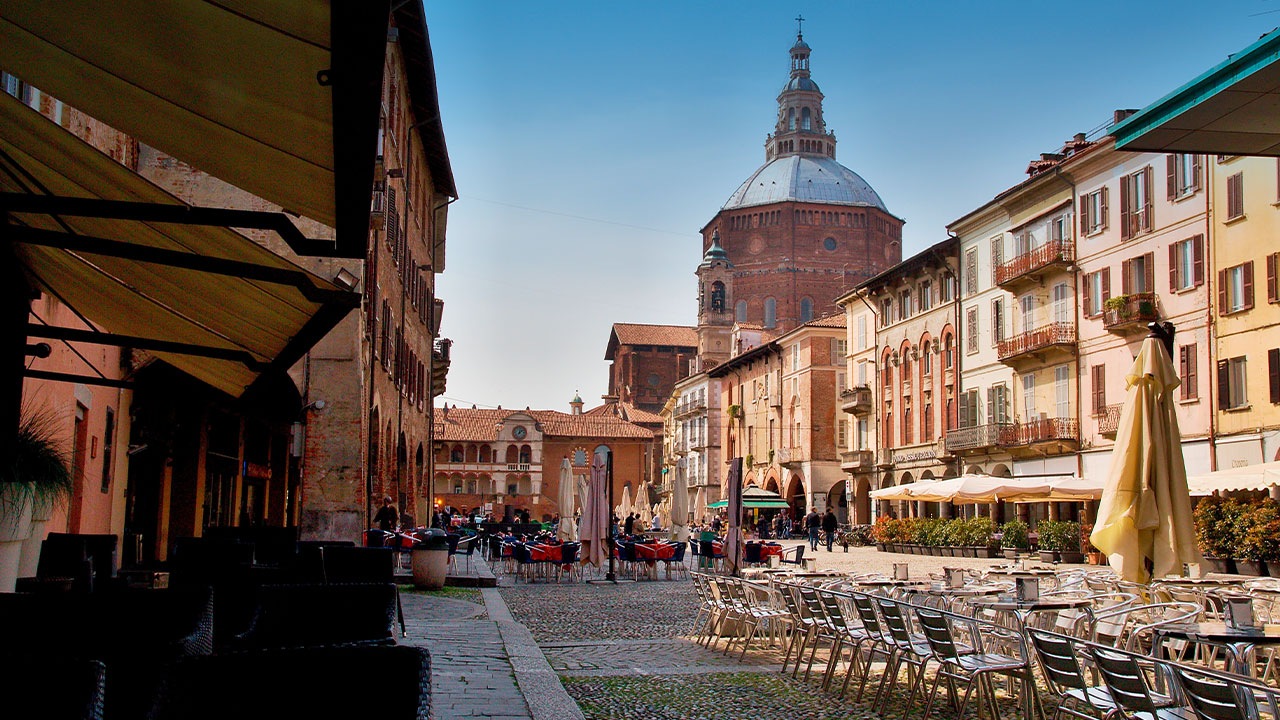 A wide town square, the Piazza della Vittoria, with colorful rows of houses and seats.